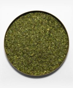 Imagem em fundo branco de uma tampa redonda com erva-mate pura folha dentro. Ervas com granulometria grossa e verde. Poucos palitos.