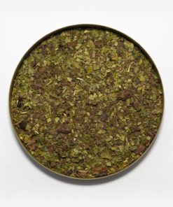 Chá mate matequero suem recipiente metálico ao centro. Fundo cinza claro. Erva-mate verde fresca pura folha com pedaços de nibs de cacau.