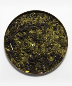Chá mate matequero em recipiente metálico ao centro. Fundo cinza claro. Erva-mate verde fresca pura folha com pedaços hortelã desitradatado com chá preto.