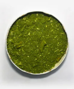 Erva-mate Composta Mate Nativo em recipiente metálico no centro. Fundo cinza claro. Erva-mate verde fresca. Pouca presença de palitos. Palitostriturados. Erva-mate padrão gaúcho composta de laranja e menta.