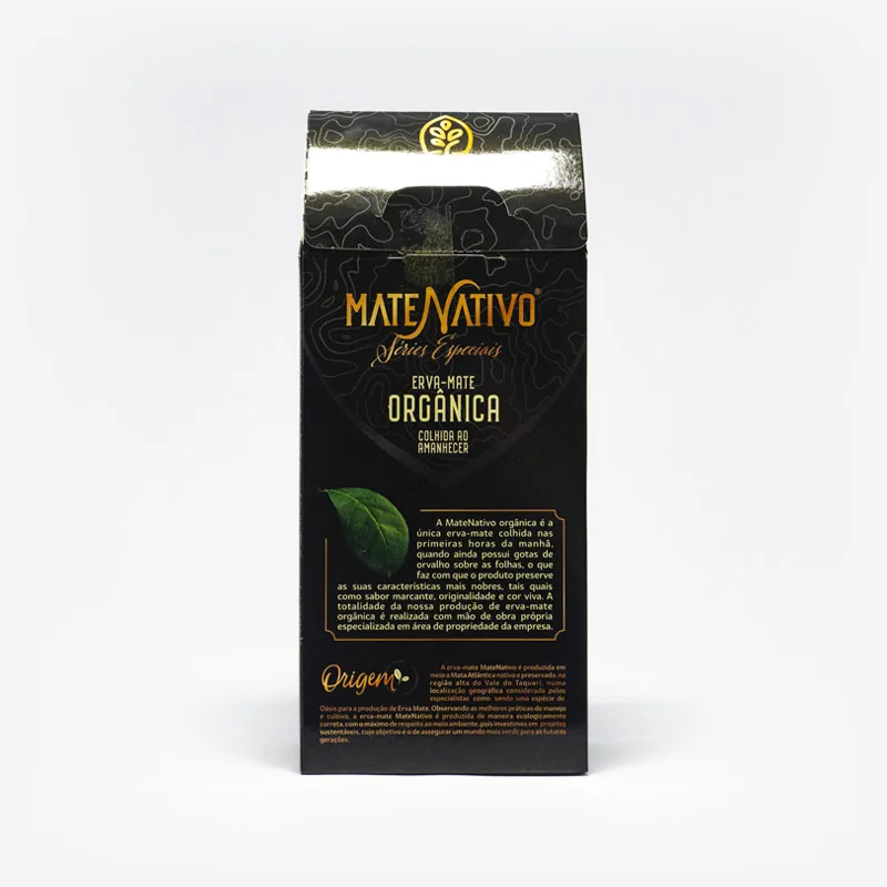 Erva-mate orgânica colhida no amanhecer. Pacote de 500 gramas em fundo branco virada de costas. Pacote preto com detalhes cinzas. Pacote verde escuro com detalhes em amarelo e com logo escrita em amarelo. Maiores informações ilegíveis.
