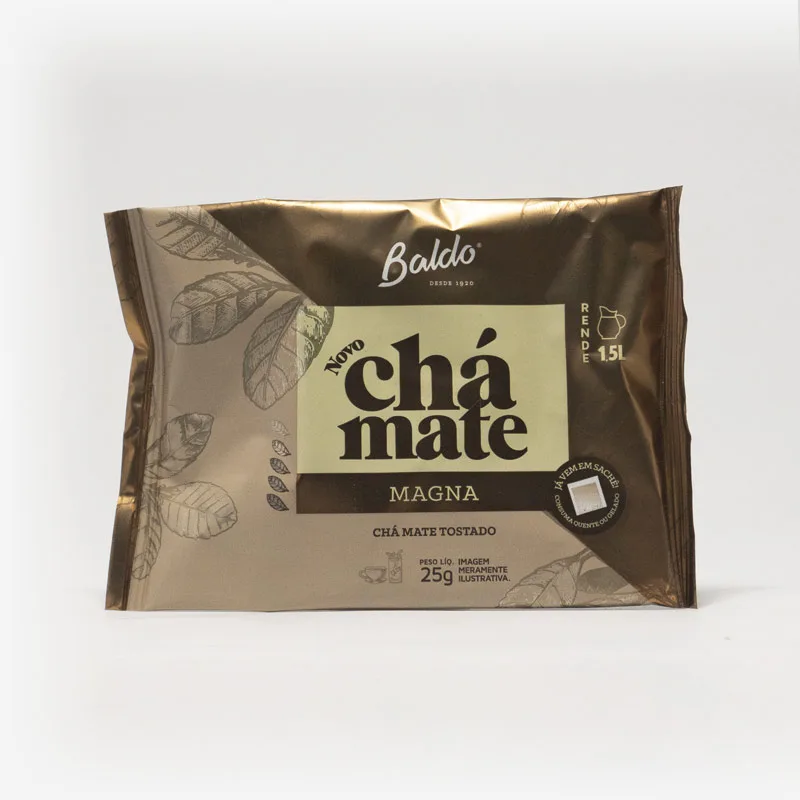 Pacote de chá mate magna em fundo cinza claro. Pacote com tons de marrom. Detalhes escuros no canto superior direito, formando um triângulo. Em escrito: Baldo, novo chá mate magna. Chá mate tostado. 25 gramas.