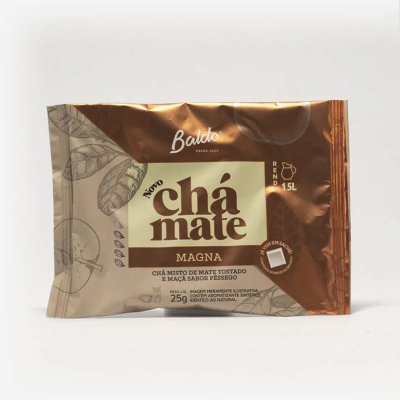 Pacote de chá mate magna em fundo cinza claro. Pacote com tons de marrom com laranja escuro. Detalhes laranja escuro no canto superior direito, formando um triângulo. Em escrito: Baldo, novo chá mate magna. Chá misto de mate tostado e maçãs sabor pêssego.