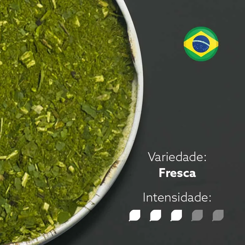 Erva-mate Chimarrão Orgânica Mate Nativo em recipiente metálico ocupando metade esquerda da imagem. Fundo cinza escuro e bandeira do Brasil circular no canto superior direito. Em escrito: Varidade Fresca com intensidade nível 3 de 5.