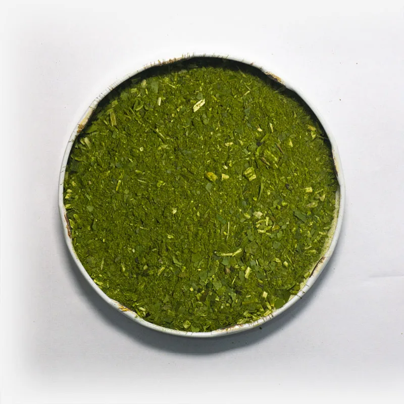 Erva-mate Chimarrão Orgânica Mate Nativo em recipiente metálico no centro. Fundo cinza claro. Erva-mate verde fresca com pouca ou nenhuma presença de palitos. erva-mate verde fina.